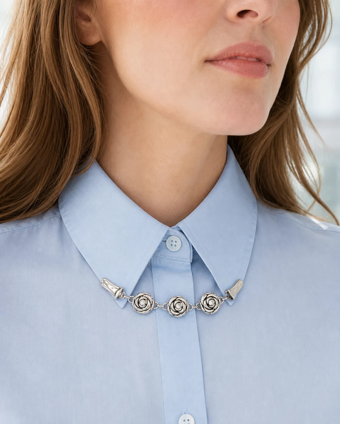 Open rose chain clip worn beneath the points of a pale blue shirt collar